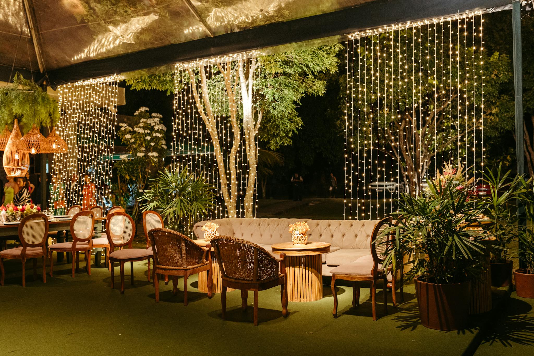 Charming outdoor seating area with elegant lights and greenery, perfect for relaxed gatherings at night.