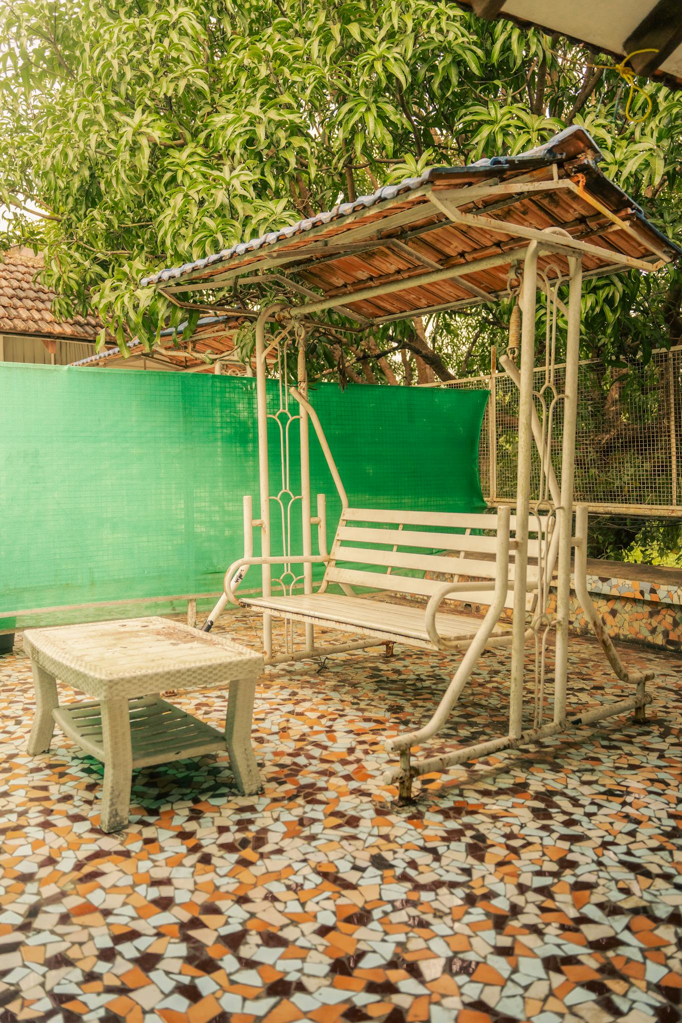 Rustic outdoor swing with patterned floor in Anjuna, Goa. Ideal for relaxation and leisure.